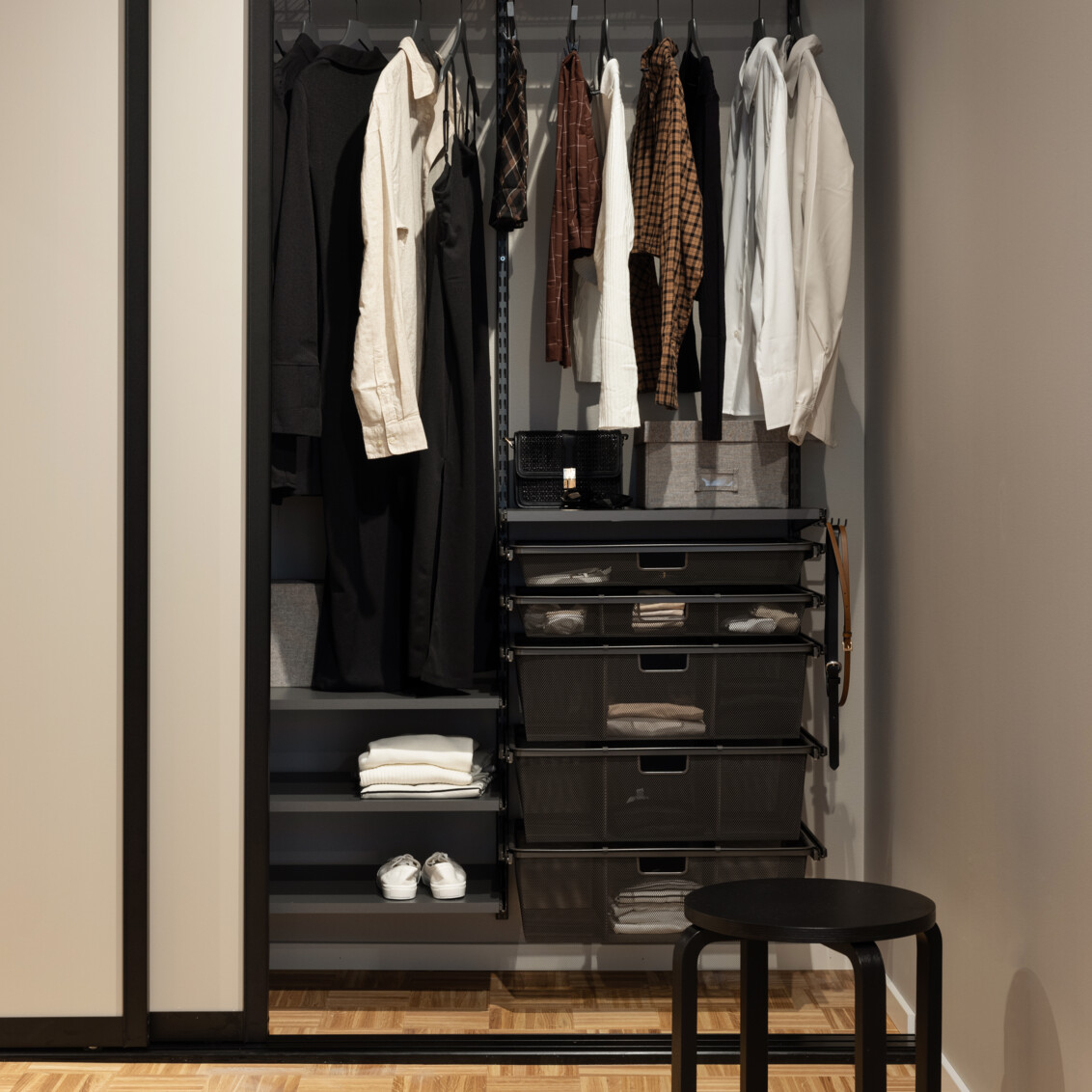 Klädförvaring på klädstång och trådhyllor i garderob med skjutdörrar.