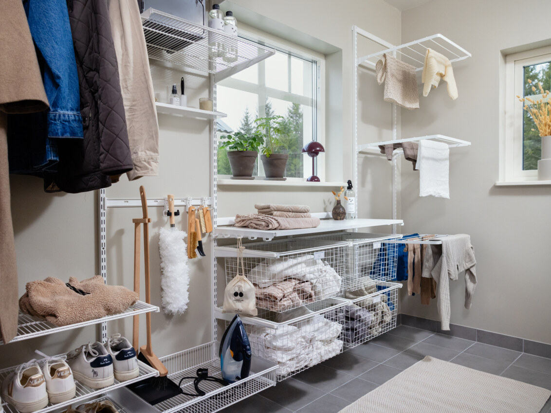 Pesuhuone, jossa on Classic by Elfa -säilytyskalusteet, jotka koostuvat hyllyistä, koreista ja kuivaustelineistä.