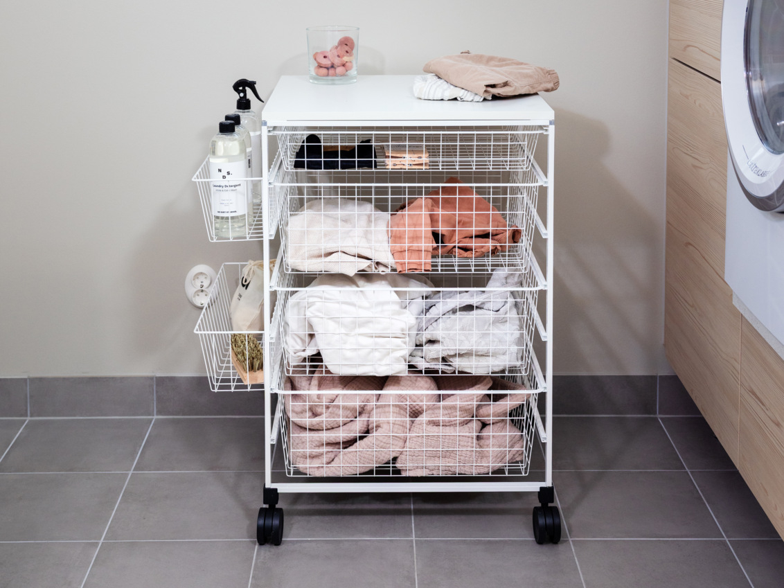 Pesuhuone, jossa on Classic by Elfa -rullakorijärjestelmä ja verkkokorit, jotka sisältävät pesutuotteita.