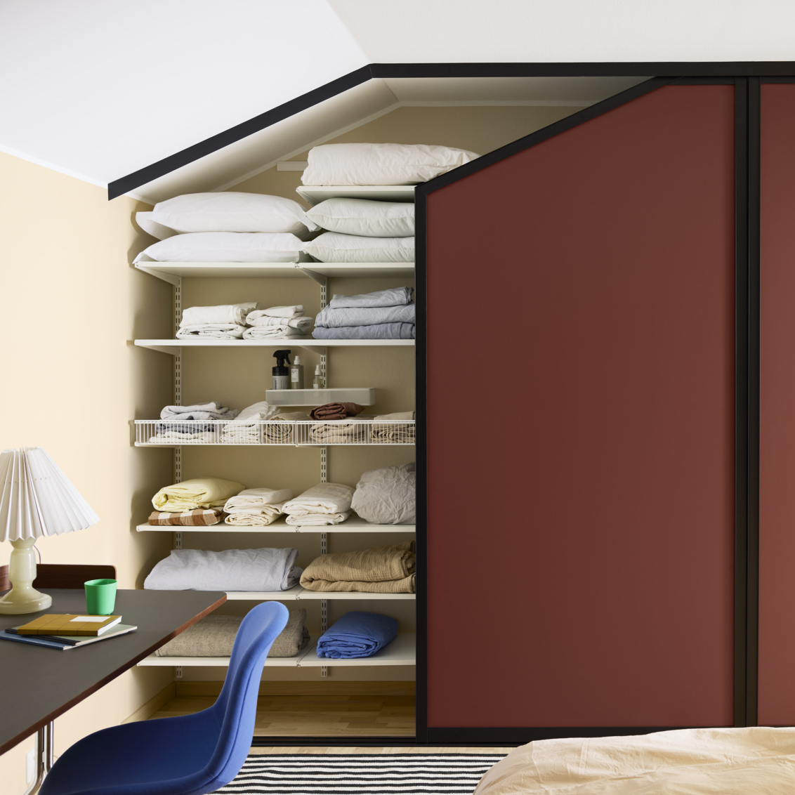 Sovrum med garderob som har vinröda skjutdörrar från Elfa, under snedtak.