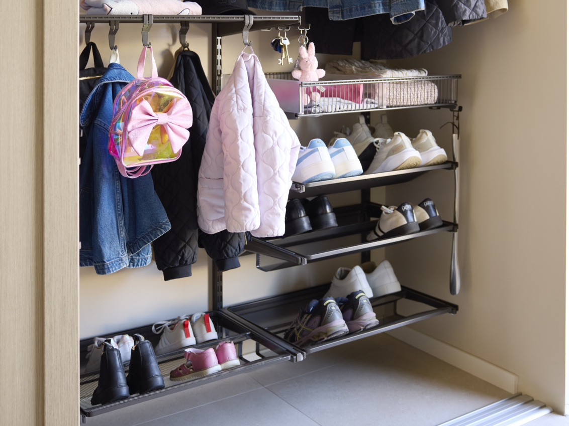  Hall med en garderob från Elfa med tunna jackor, skor och en ryggsäck för barn.