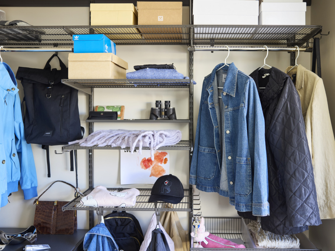 Graderob från Classic by Elfa i grått med tunna jackor, halsdukar och väskor.