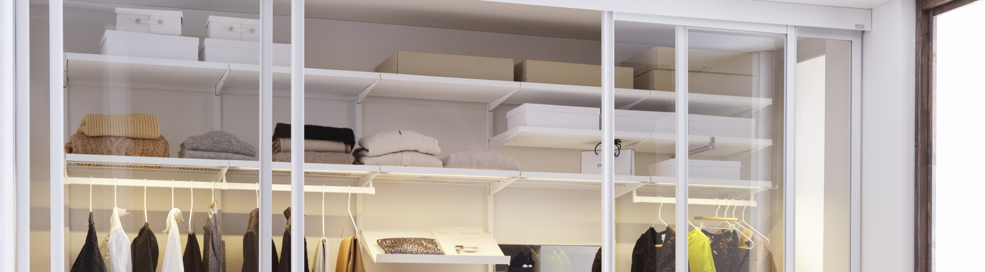 Garde-robe Décor+ d’Elfa en blanc avec étagères et vêtements suspendus.