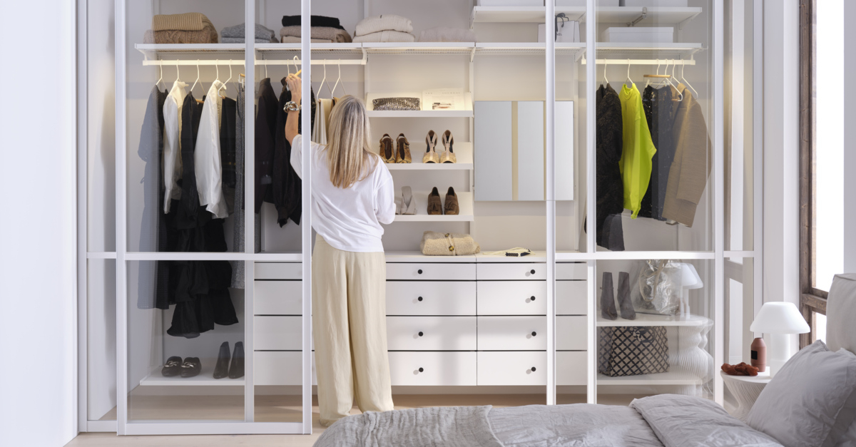 Nainen seisoo vaatekaapin edessä, jossa on Elfan Décor+ säilytyskalusteet ja Artic lasiliukuovet.