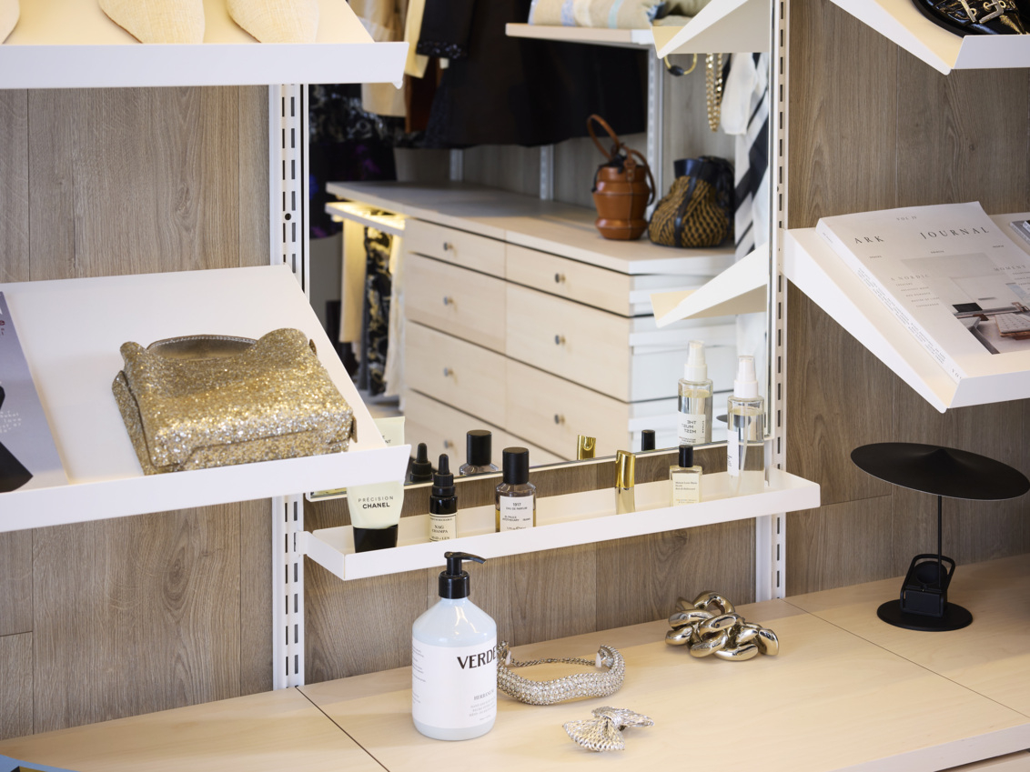 Walk-in closet with Décor+ mirror surrounded by angled shelves with accessories.