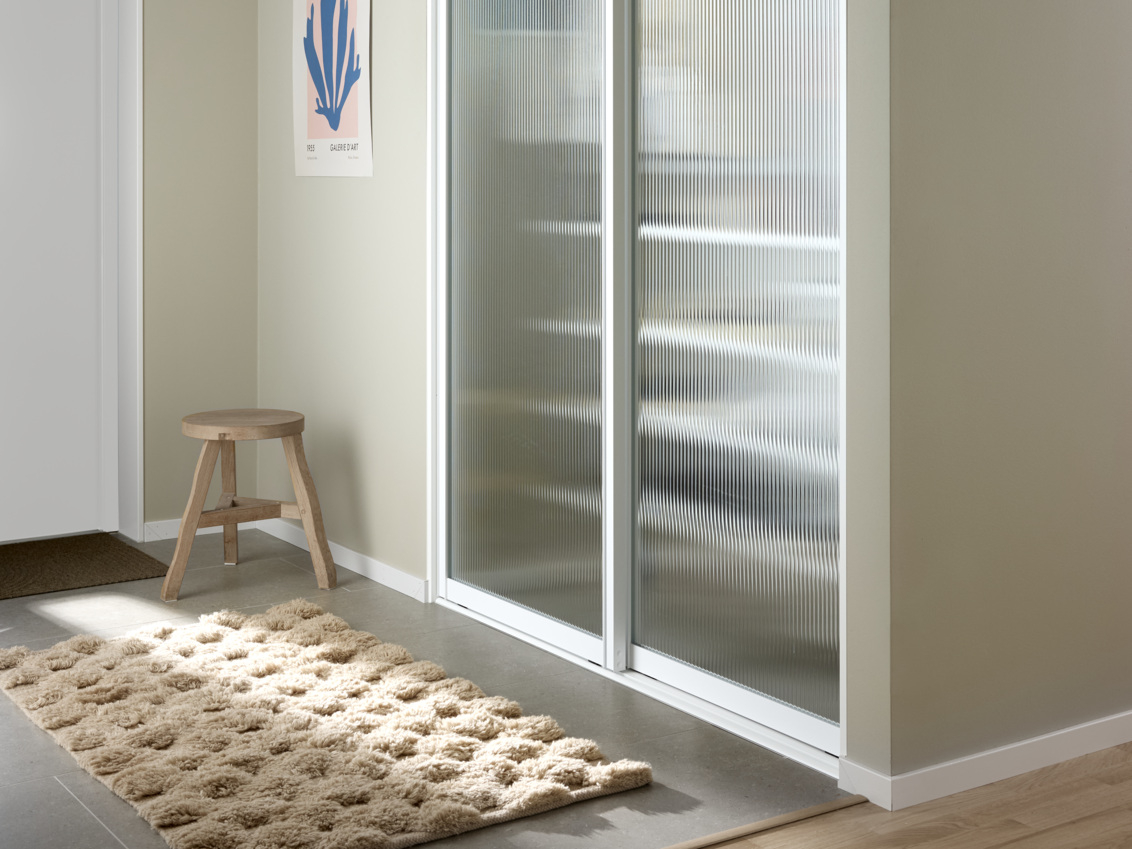 Eteinen, jossa on Classic by Elfa -vaatekaappi ja Artic-liukuovet linjalasilla.