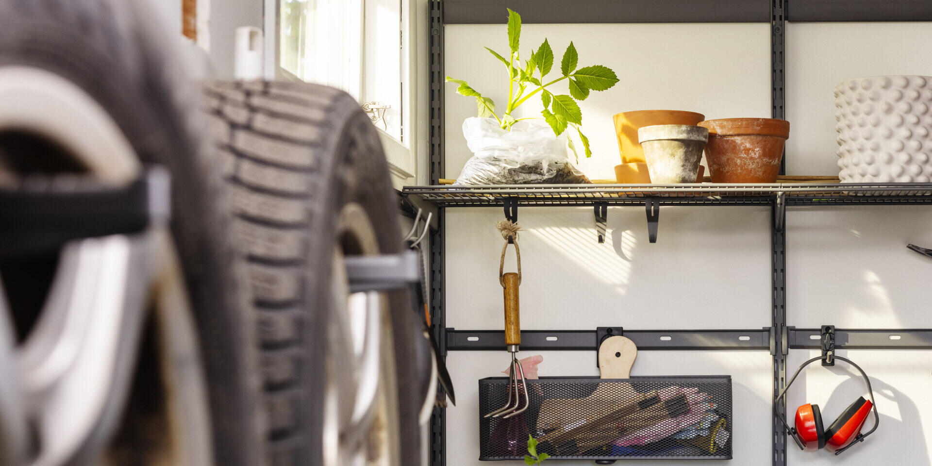 Garage med Garage+ förvaring från Elfa med trådhyllor och förvaringslist där det förvaras krukor och trädgårdsverktyg.