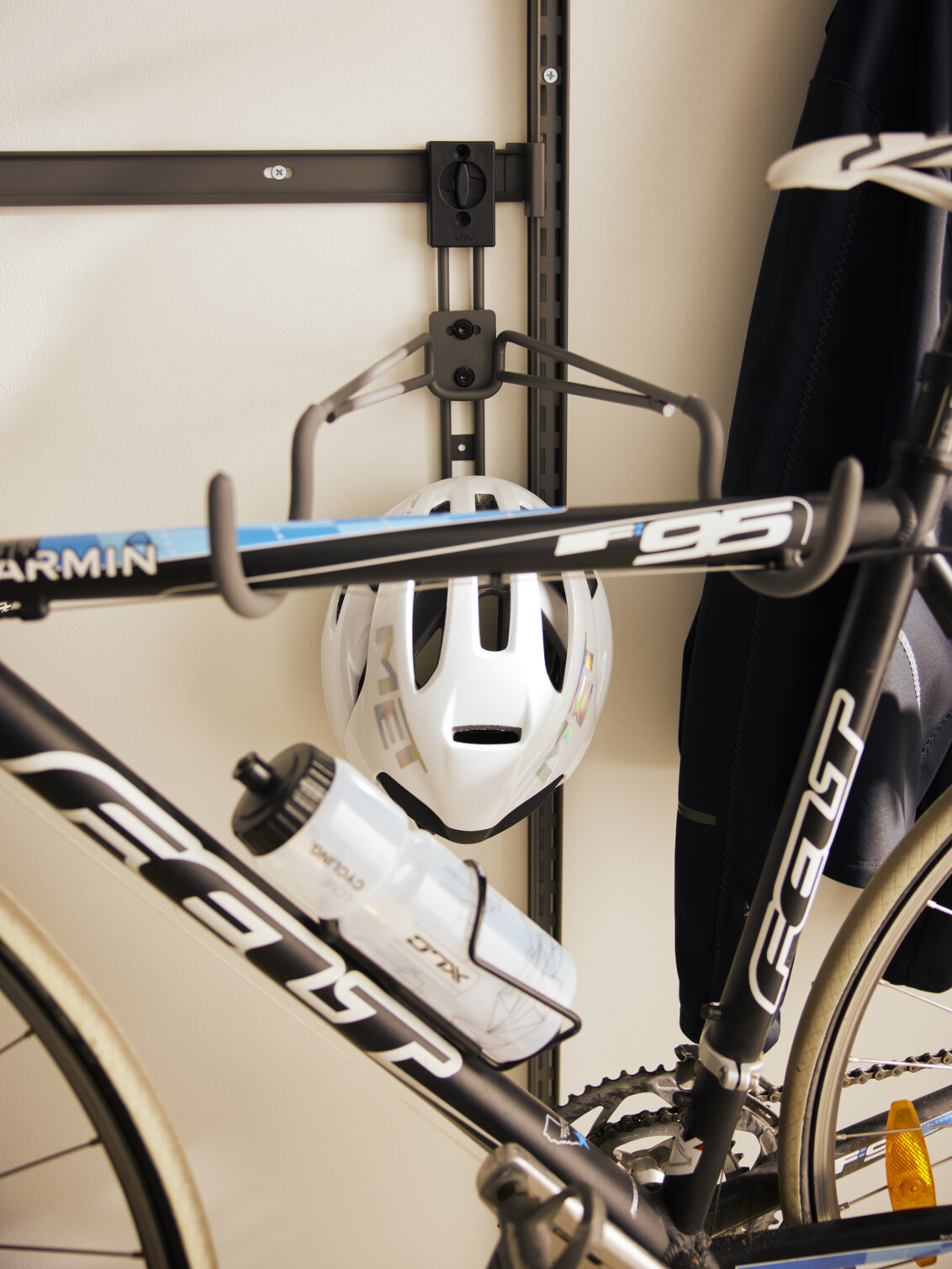 En cykel och en hjälm hänger i en horisontell cykelkrok från Garage+ by Elfa.