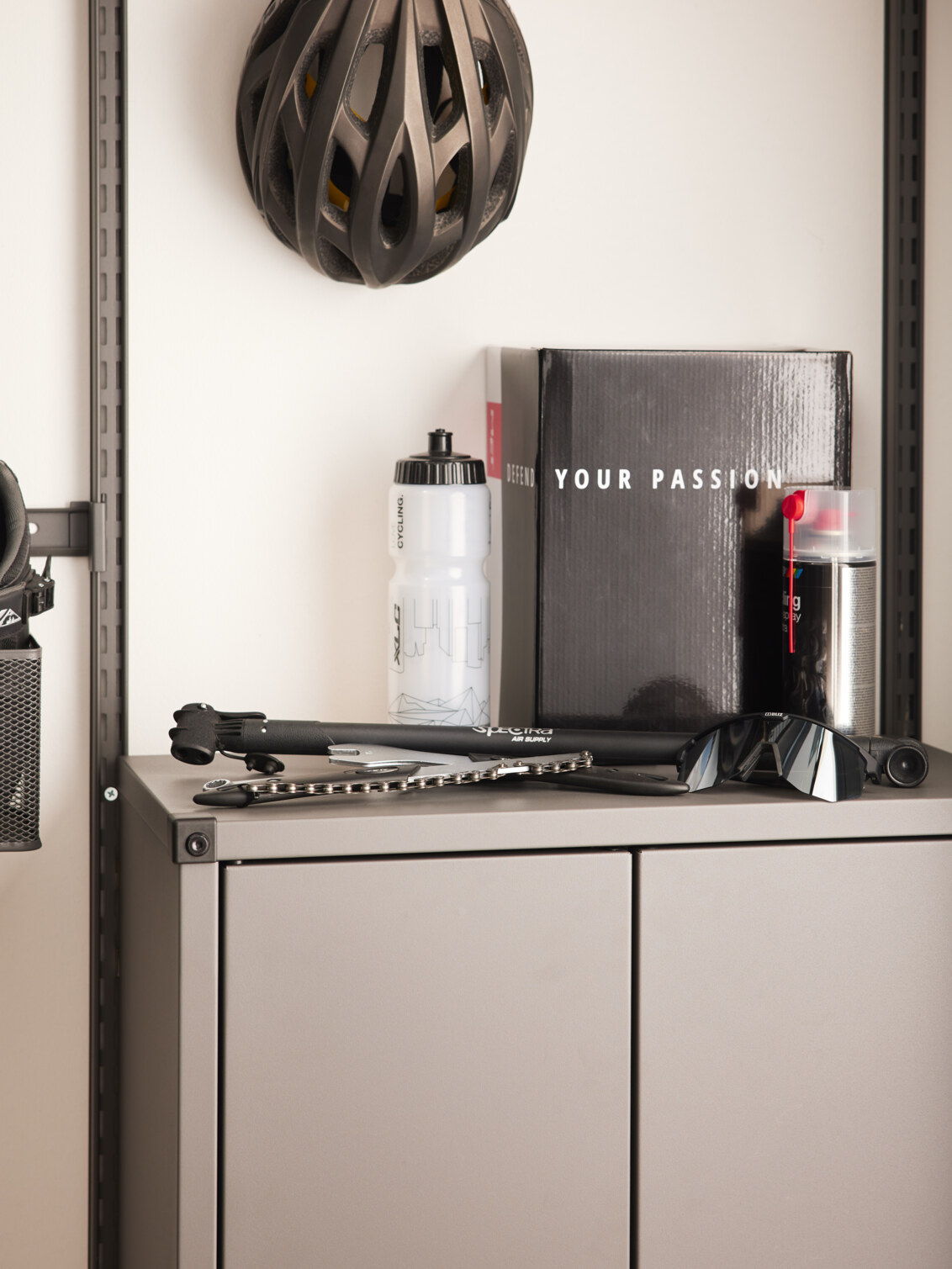 Cykelkedja, vattenflaska och cykelmpump ovanpå ett skåp från Garage+ by Elfa.