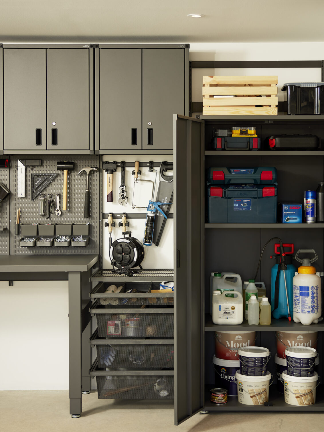 Garaje con almacenamiento Garage+ de Elfa con armarios y contenedores de malla para almacenar herramientas.