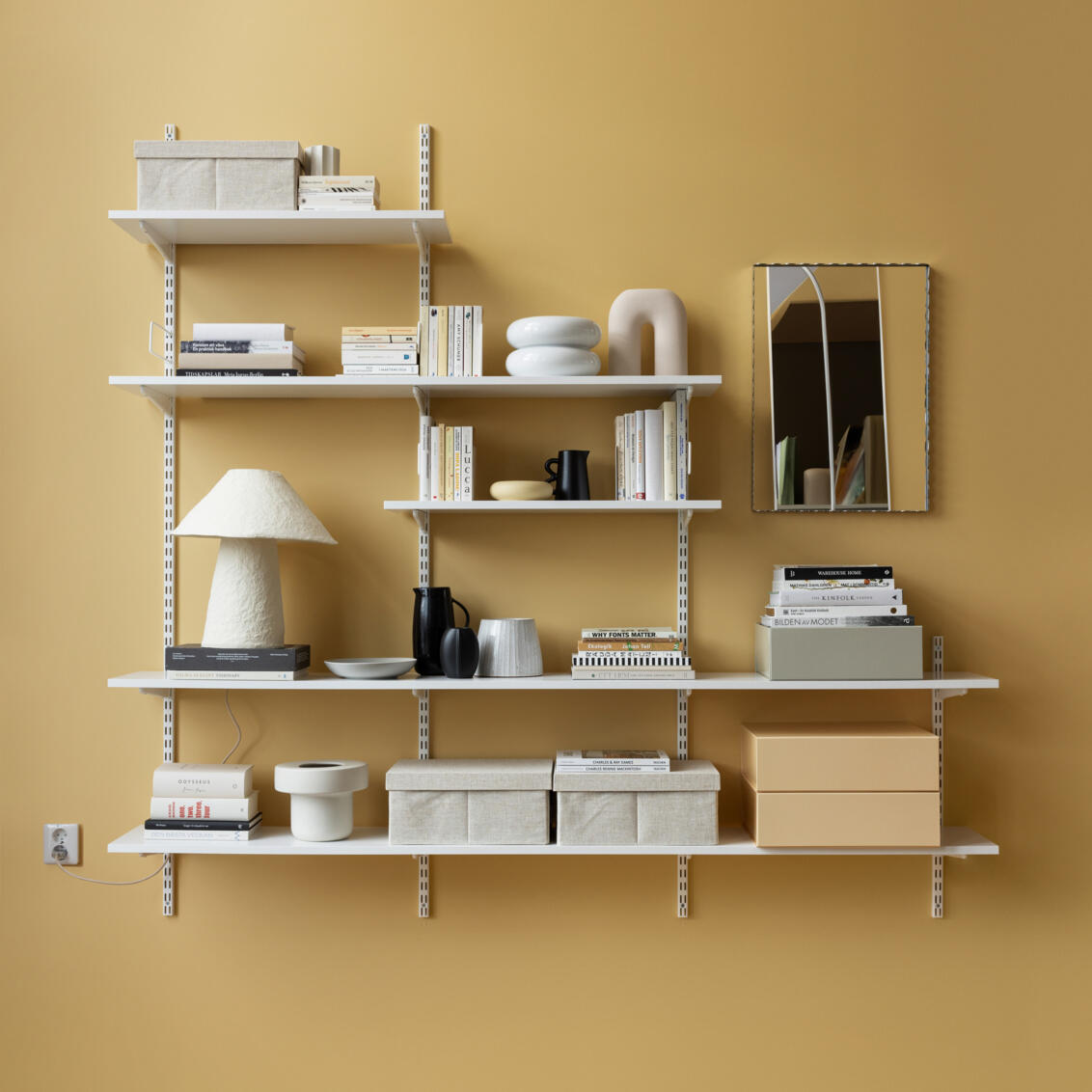 Sparring bookcase from Elfa in white with books, storage boxes and decorative items.