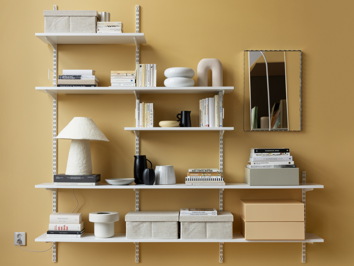 Valkoinen Elfan Sparring kirjahylly, jossa on kirjoja, säilytyslaatikoita ja koriste-esineitä.