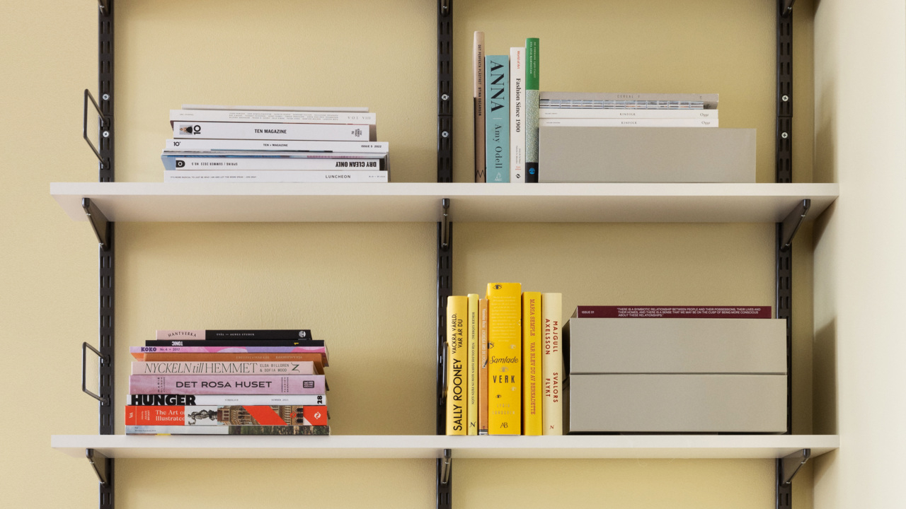 Librería con largueros de Elfa con bandas de pared en gris y estantes de melamina en blanco.