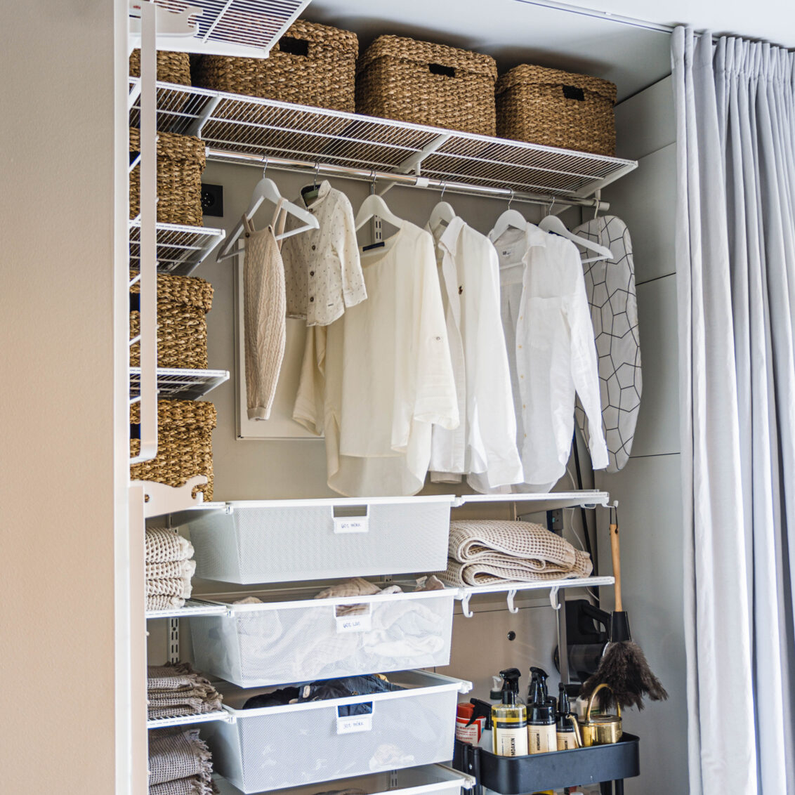 Pesula, jossa on Classic by Elfan valkoinen säilytyskaluste, roikkuvia vaatteita ja verkkokoreja pyykille.