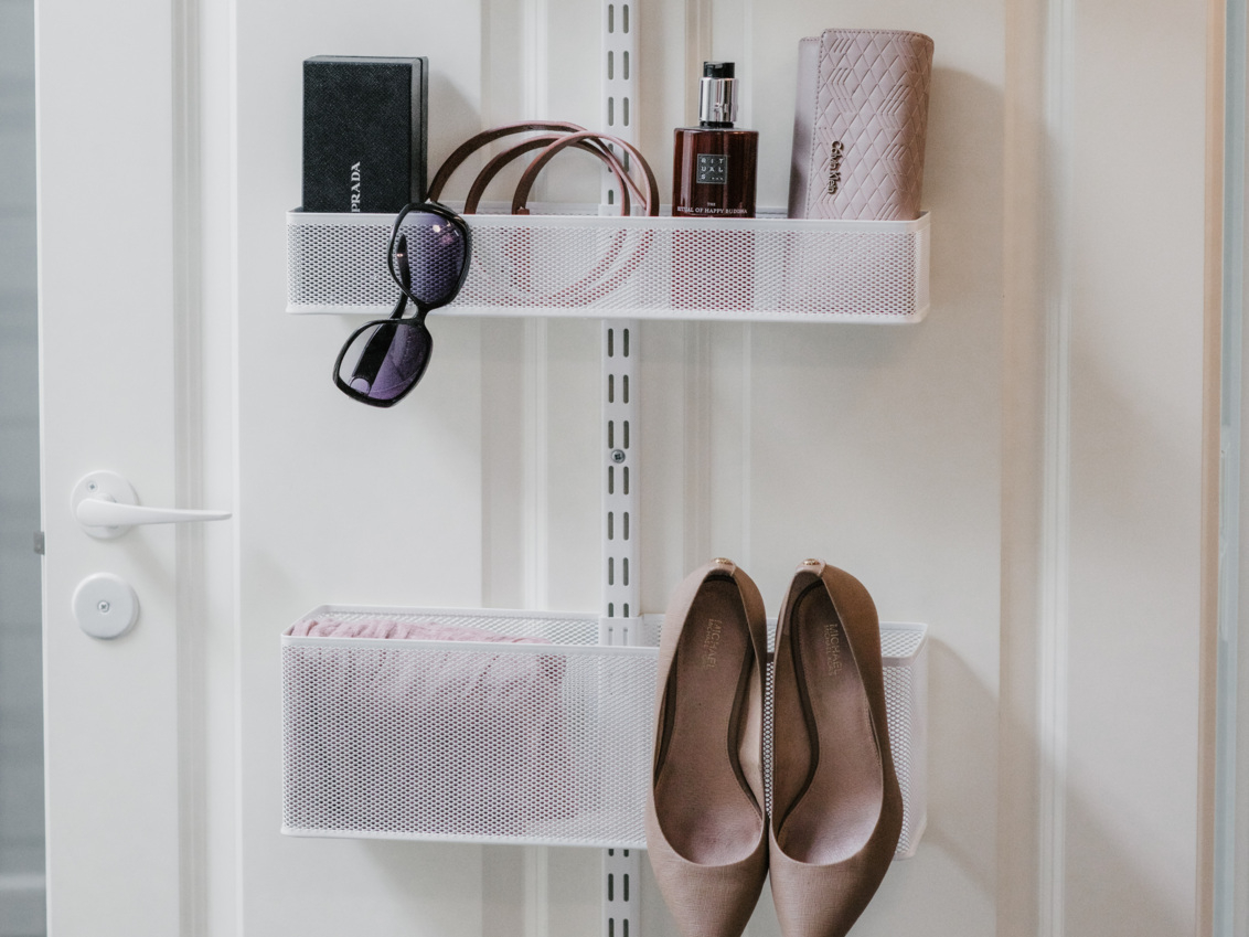 Door with Classic by Elfa storage in white with mesh baskets containing shoes and accessories.