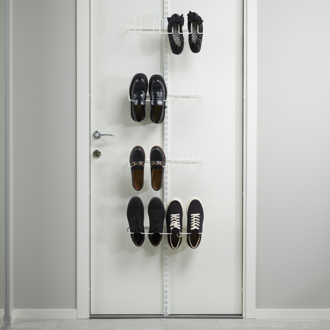 Valkoinen ovi ja Classic by Elfan kenkäsäilytyssarja, jossa roikkuu viisi mustaa kenkäparia.