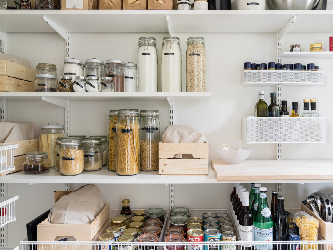 Skafferi med hyllor och trådhyllor från Elfa fyllda med glasbrukar, kryddor och flaskor.