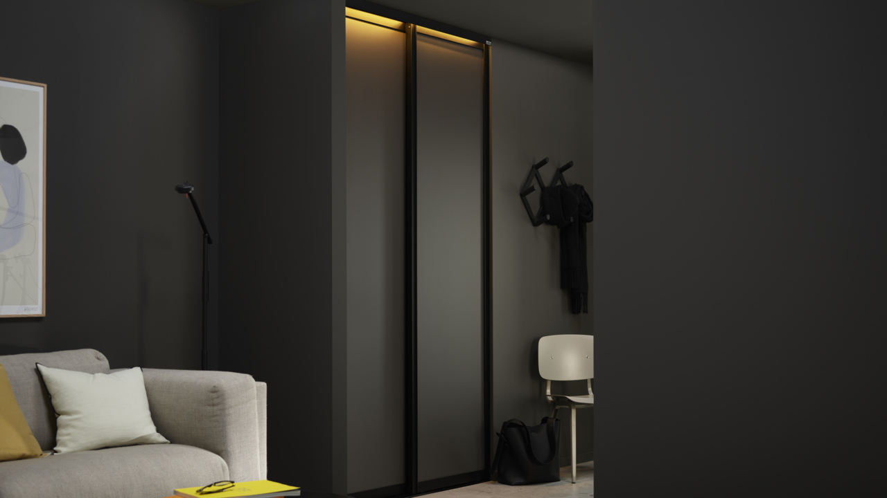 Olohuone, jonka oviaukosta on näkymä Elfan vaatekaappiin, jossa on harmaat Artic-liukuovet ja LED-valaistus.