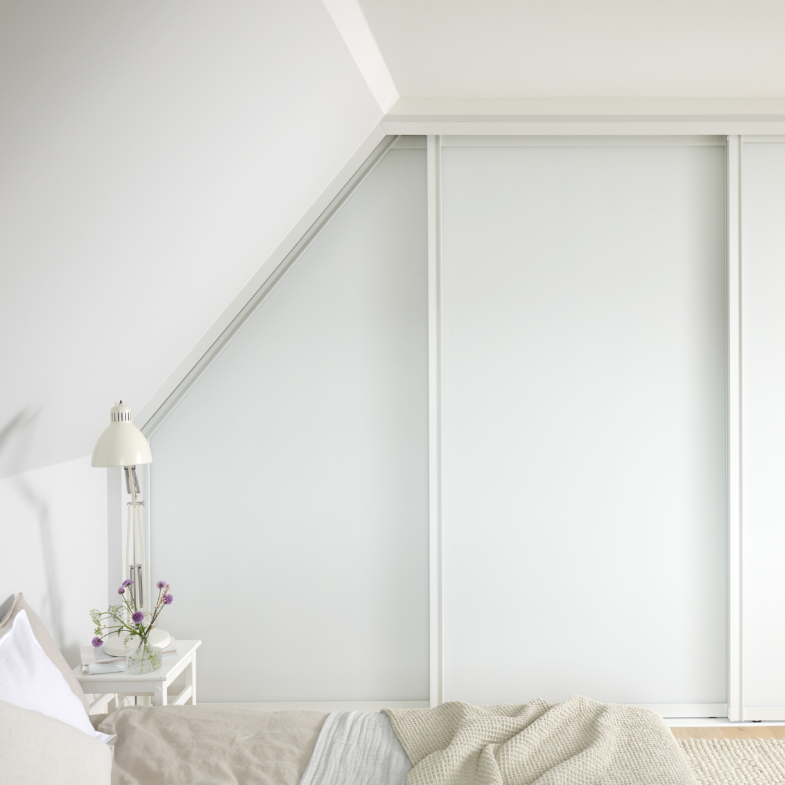 Makuuhuone, jossa on Elfan vaatekaappi, jossa on valkoiset liukuovet viistokatossa.