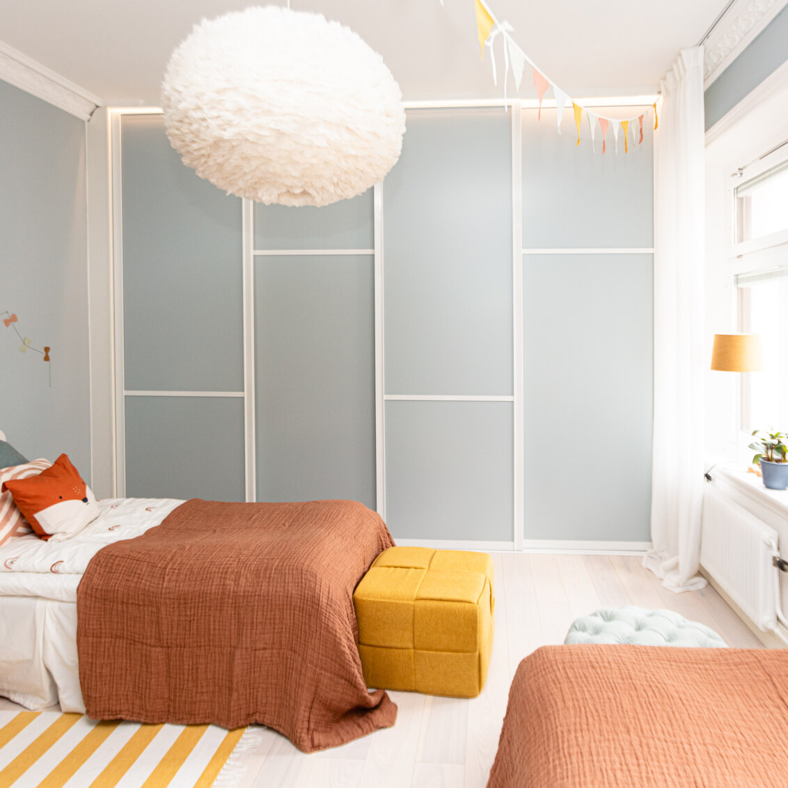 Lastenhuone, jossa on Elfa-vaatekaappi ja vaaleansiniset liukuovet.