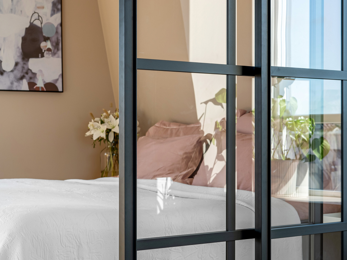 Makuuhuone, jossa on Elfan Artic-liukuovet, joissa on musta kehys ja lasi tilanjakajana.
