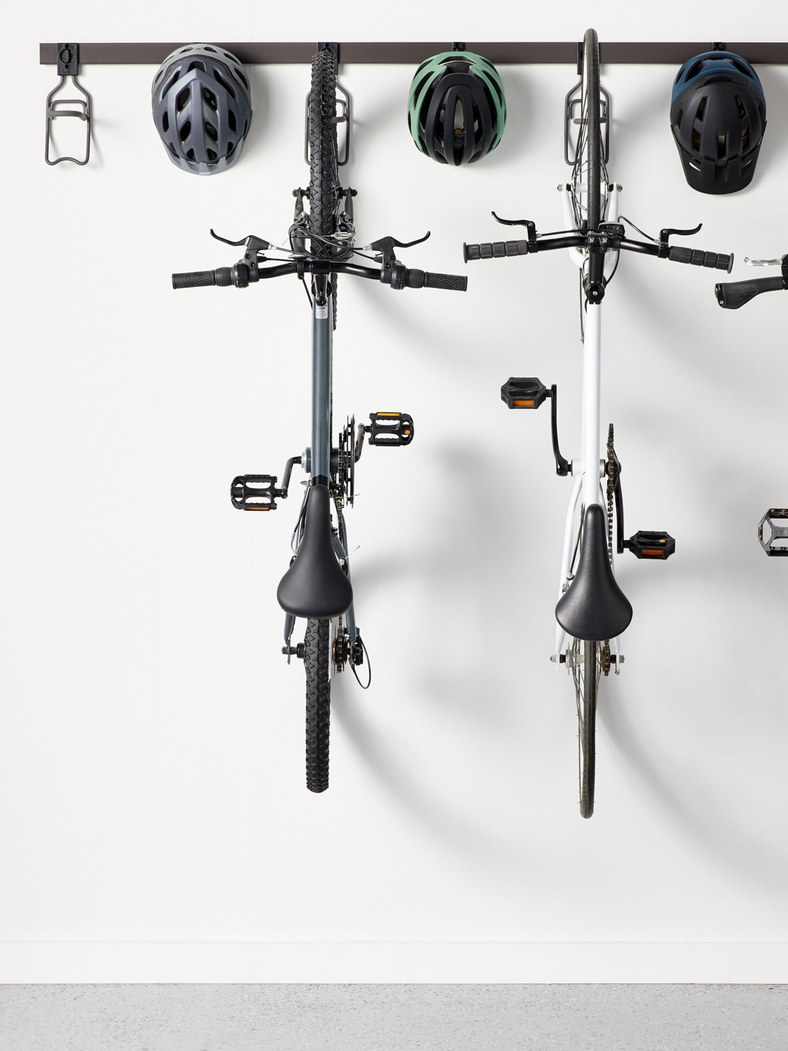 Förvaringslist från Garage+ by Elfa där det hänger cyklar och hjälmar i vertikala cykelhållare.