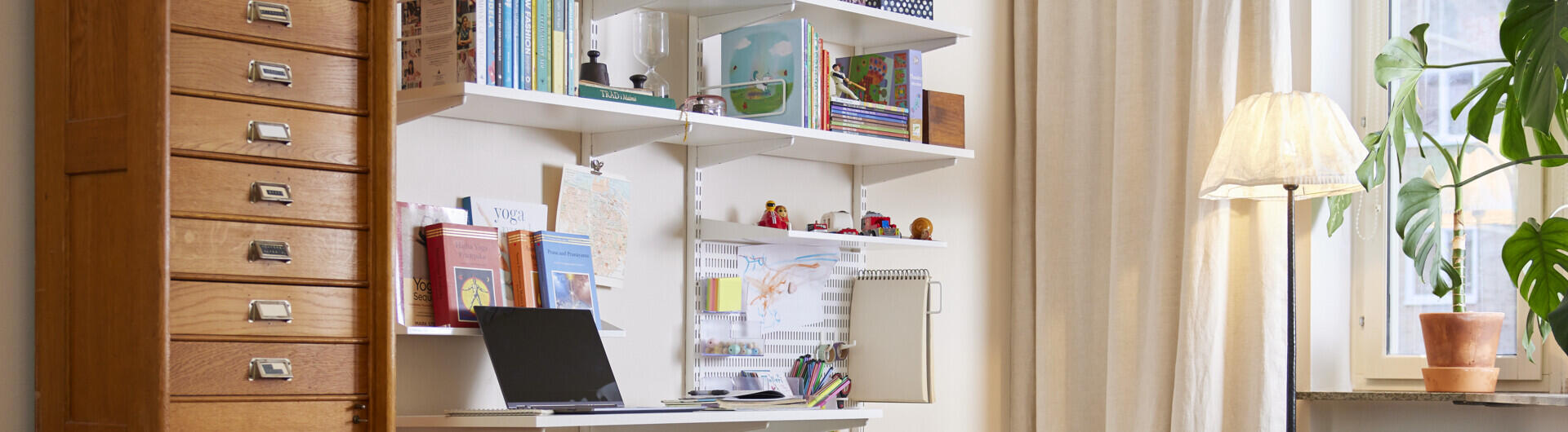 Vardagsrum med ett vägghängt hemmakontor från Classic by Elfa där en del av ytan är dedikerad till barn.