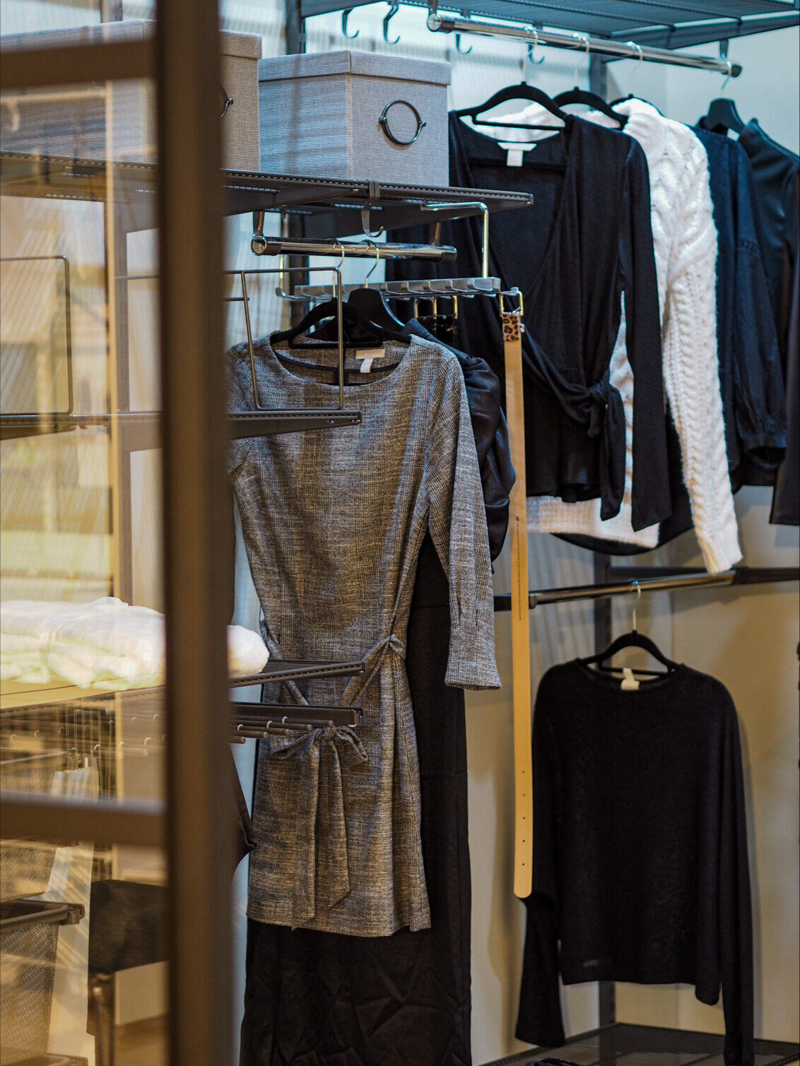 Vaatehuone, jossa vaatteet hyllyillä ja vaatetangossa.