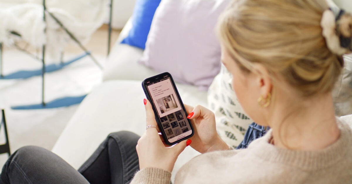 Kvinna tittar på sin telefon och använder Elfas hemsida.