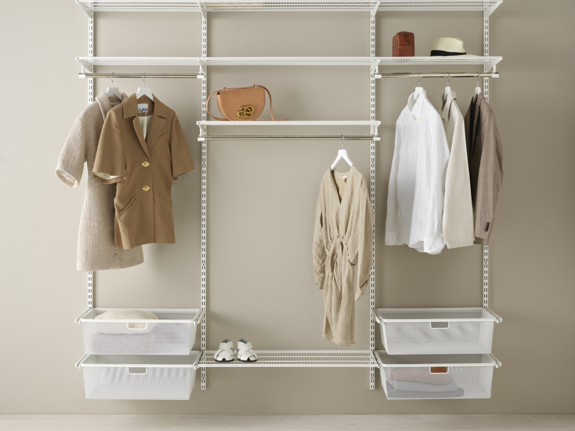 Otwarta szafa Classic by Elfa w kolorze białym, z półkami drucianymi, siatkowymi pojemnikami i wiszącą odzieżą.