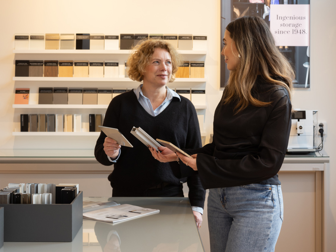 Två kvinnor som diskuterar olika färg och material val för skjutdörrar. 