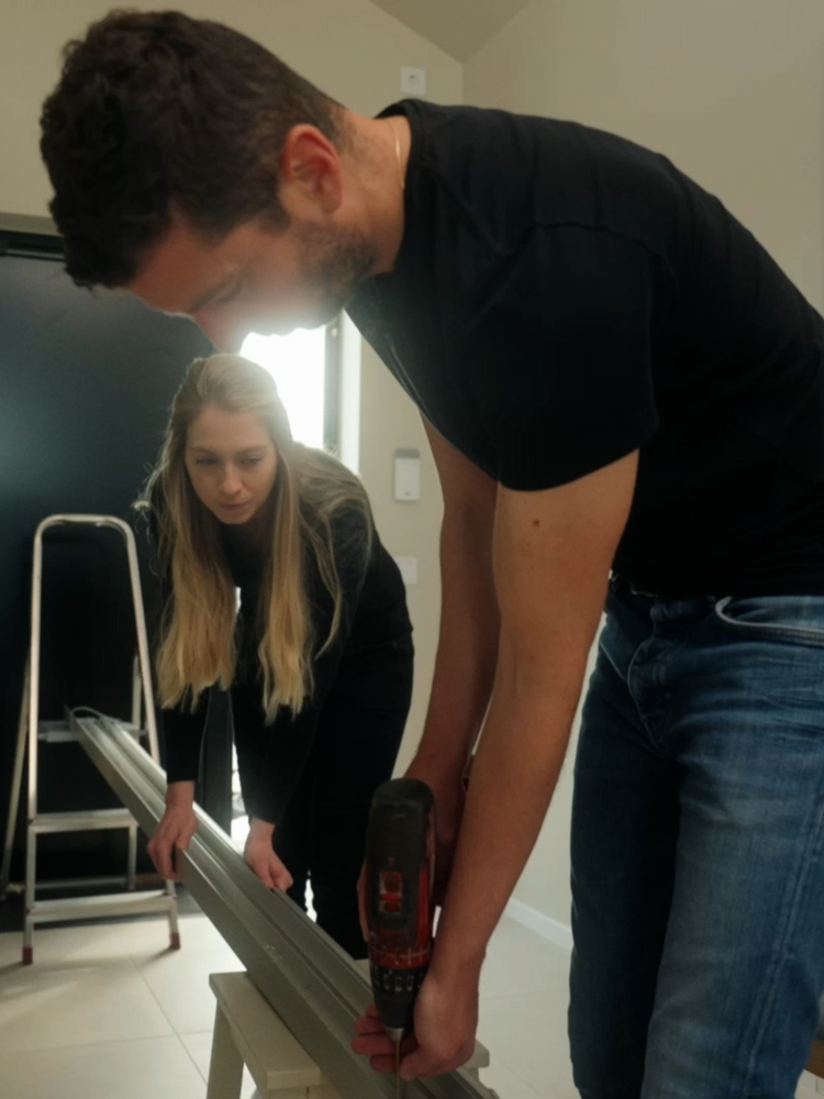 En tjej och en kille borrar en skena för skjutdörrar från Elfa.