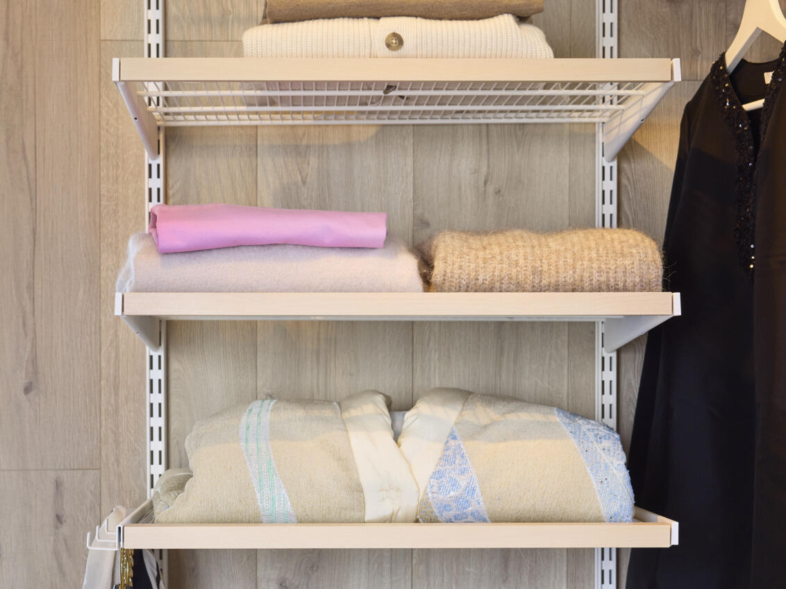 Étagères en fil métallique Décor+ d’Elfa en blanc et bouleau avec des pulls pliés.
