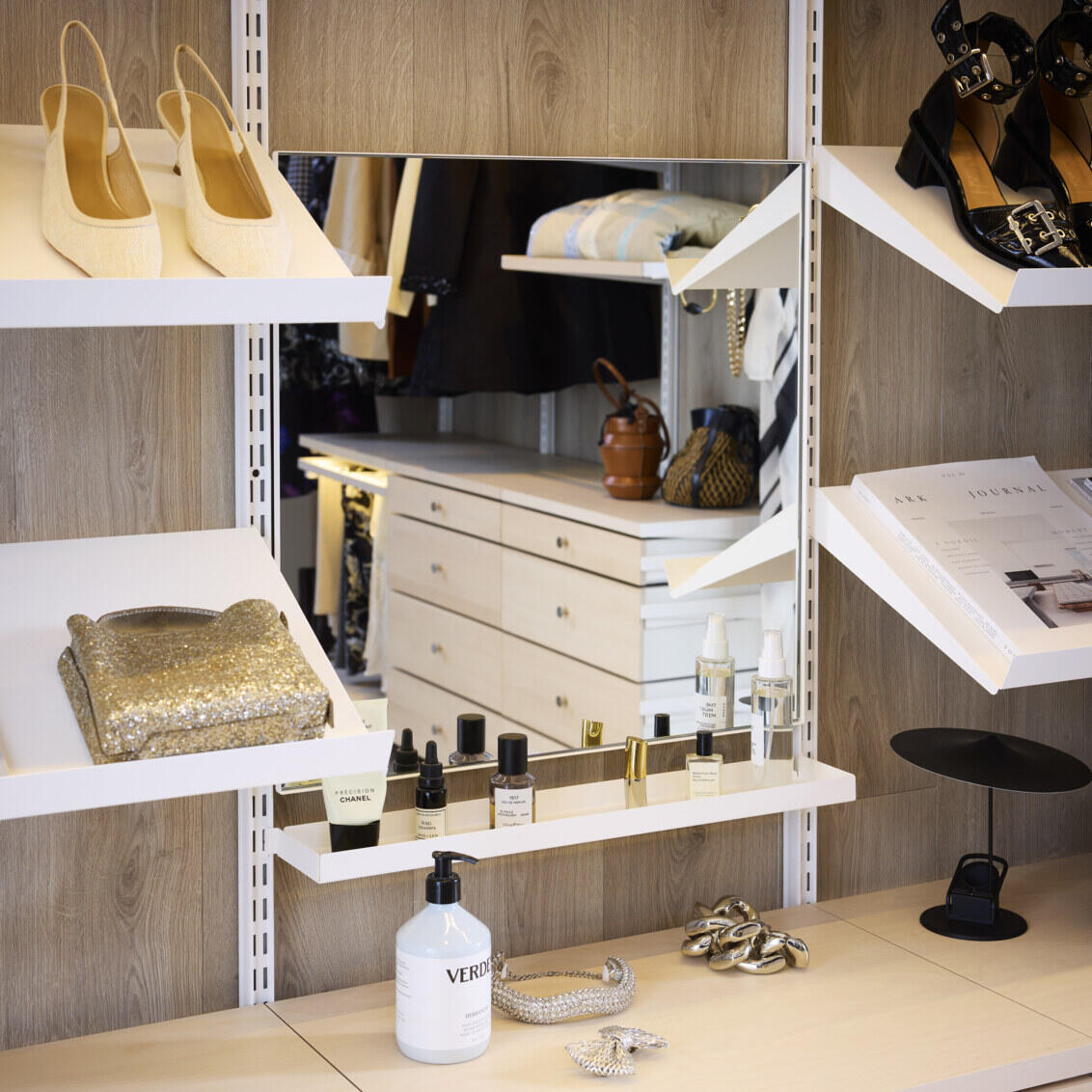 Walk-in closet with Décor+ mirror surrounded by angled shelves with accessories.